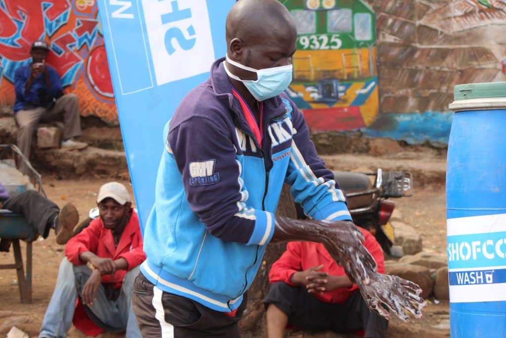 John Otieno a Kibera resident washes hands at a community hand washing station at Kamkunji grounds in Kibera-